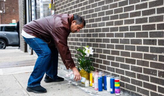 A man lights a candle at the corner where a 7-month-old baby was killed by a stray bullet while sitting in her stroller in Brooklyn Wednesday afternoon.