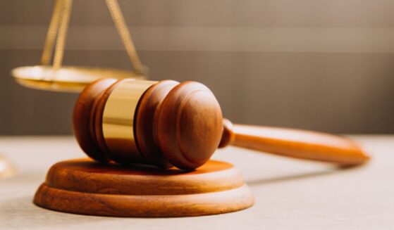 A gavel lays near a balancing scale.