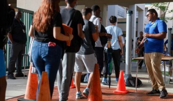 A Broward County gate supervisor examines students as they enter the campus for weapons on June 24, 2024.
