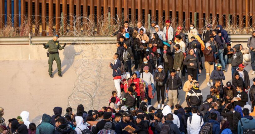 A Border Patrol agent speaks to a large crowd of immigrants blocked from entering the U.S. at the border crossing area near the Rio Grande in El Paso, Texas, on Dec. 20, 2022.