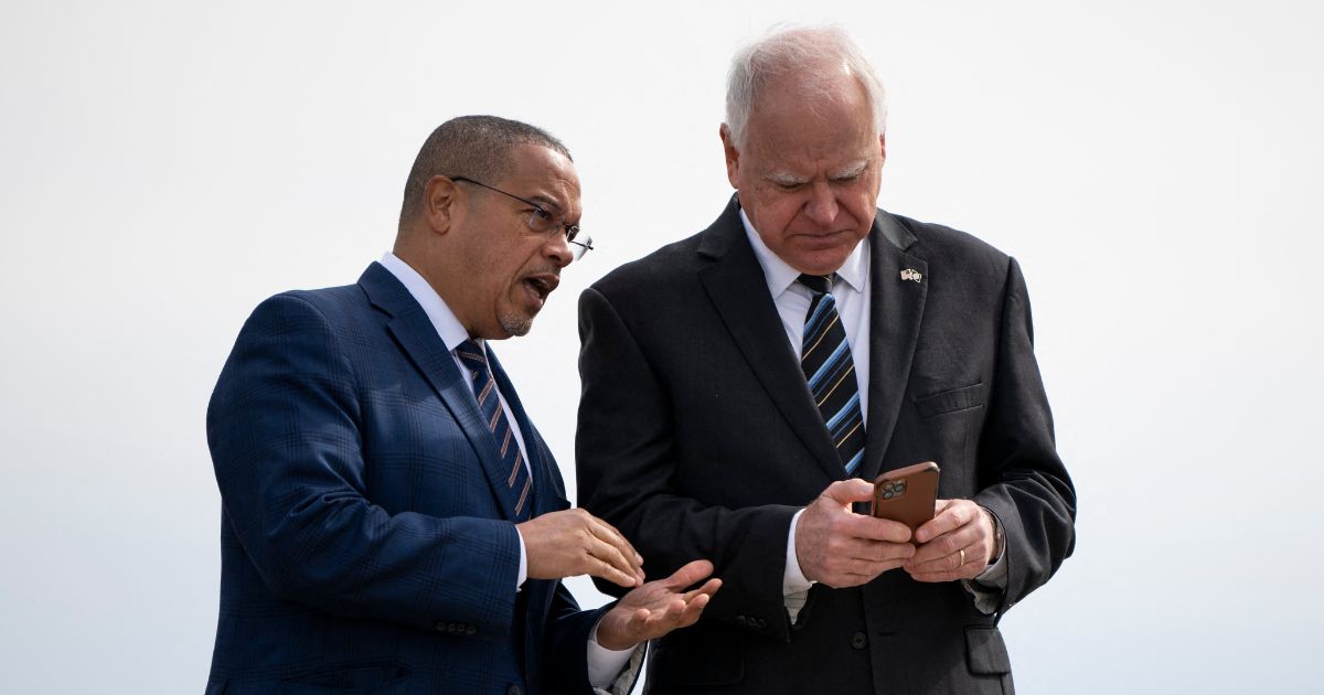 Minnesota Governor Tim Walz and Minnesota Attorney General Keith Ellison await the arrival of then-U.S. Vice President Kamala Harris at the Minneapolis-St. Paul International Airport in Saint Paul, Minnesota, on March 14, 2024.