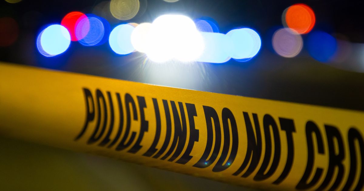 A crime scene at night covered by police tape.