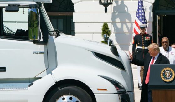 President Donald Trump reaches out to pat the hood of a truck at an event to celebrate America's Truckers at the White House in Washington, DC on April 16, 2020.