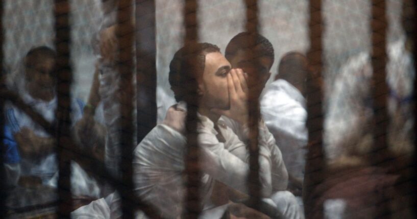 Egyptian defendants await their trial behind the bars of a jail in Cairo on May 30, 2015.