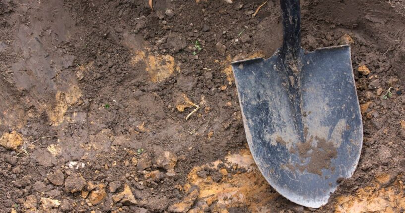 A close-up of a shovel in the dirt.