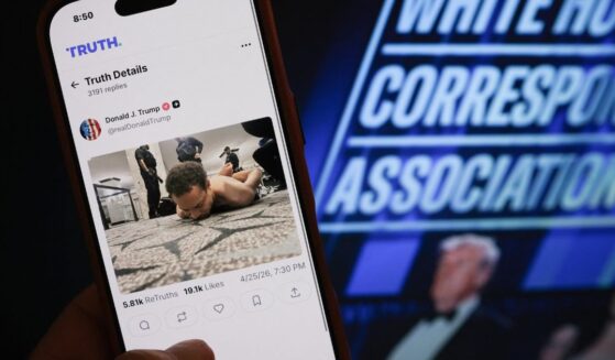 Someone holds a phone with a picture of a post published by President Donald Trump on Truth Social showing the alleged shooter accused of opening fire at the White House Correspondents' dinner in Washington, DC on April 25, 2026.