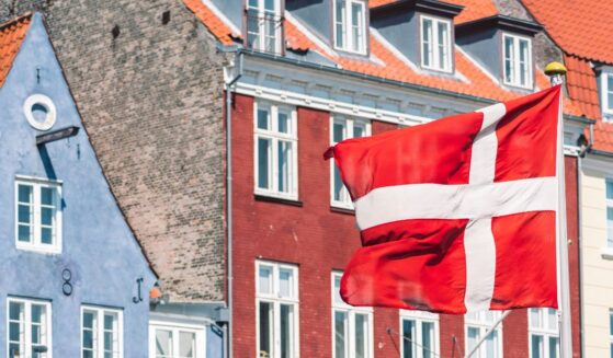 A Danish flag flies in front of traditional houses in Copenhagen.