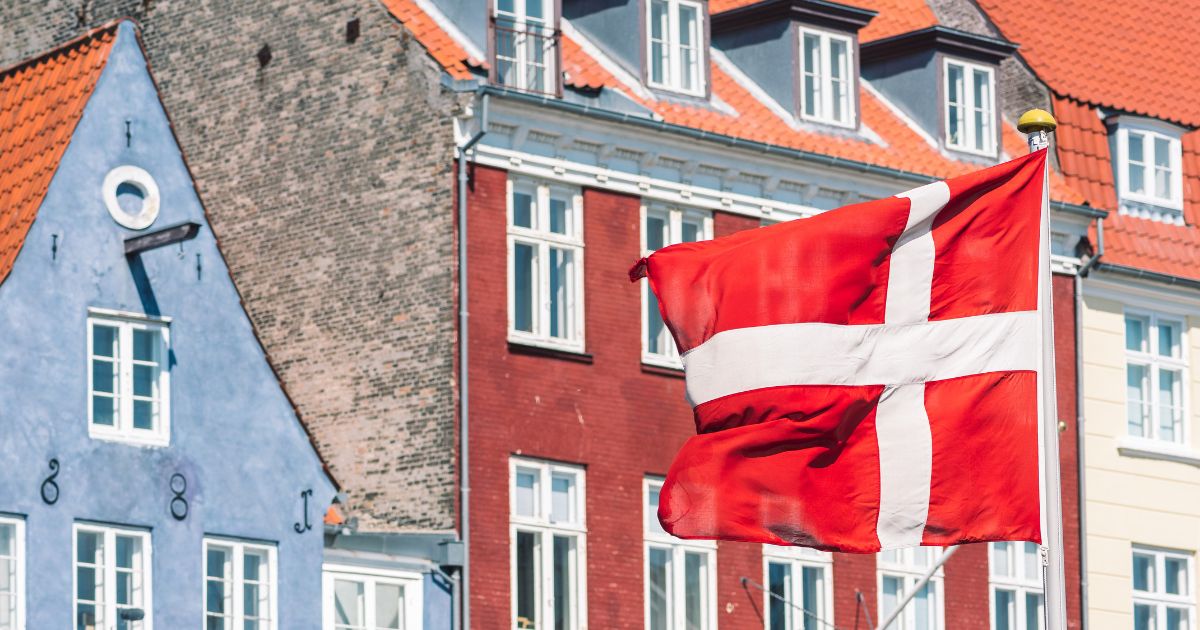 A Danish flag flies in front of traditional houses in Copenhagen.