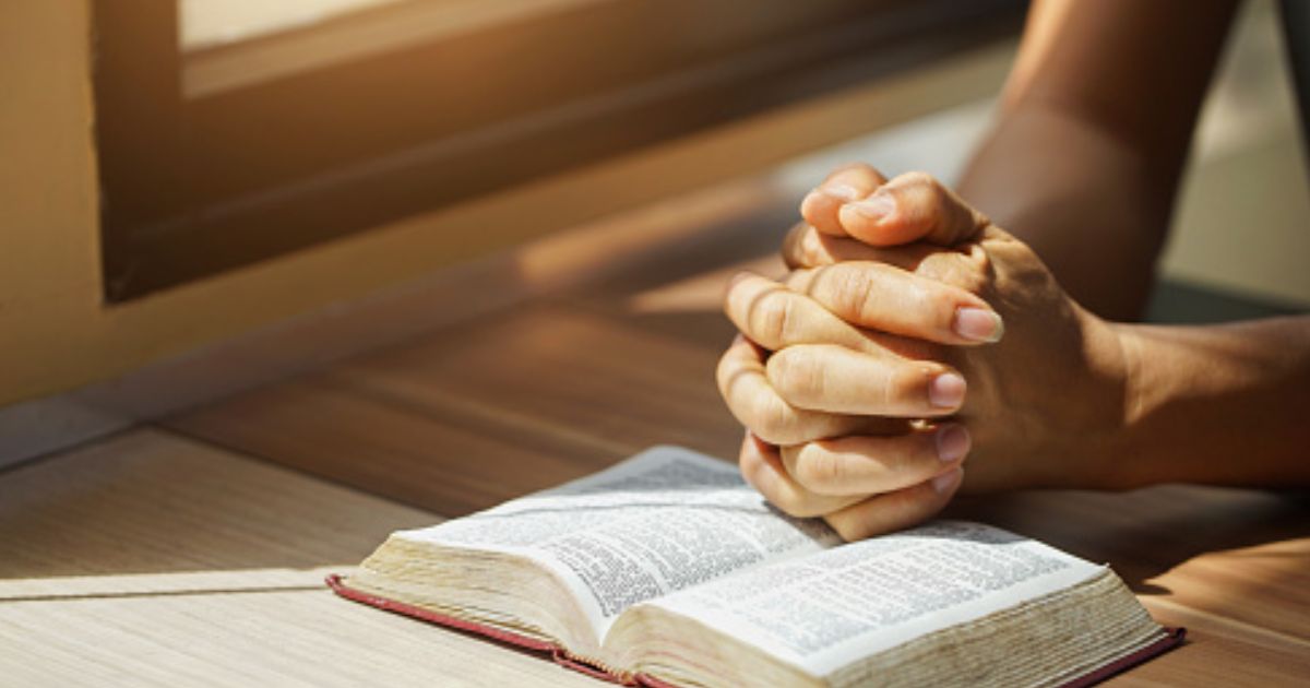Hands on the Bible in a prayerful position.