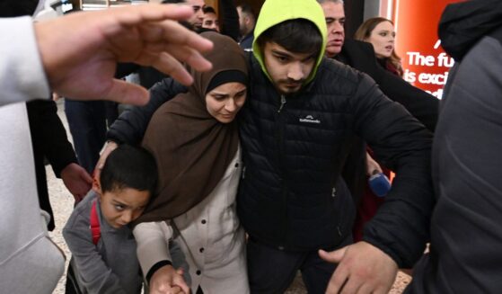 A woman who is accused of ties to the Islamic state is escorted through a crowd by supporters on Thursday, May 7, 2026. (Joel Carrett / AAP Image via AP)