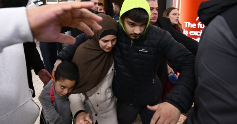 A woman who is accused of ties to the Islamic state is escorted through a crowd by supporters on Thursday, May 7, 2026. (Joel Carrett / AAP Image via AP)