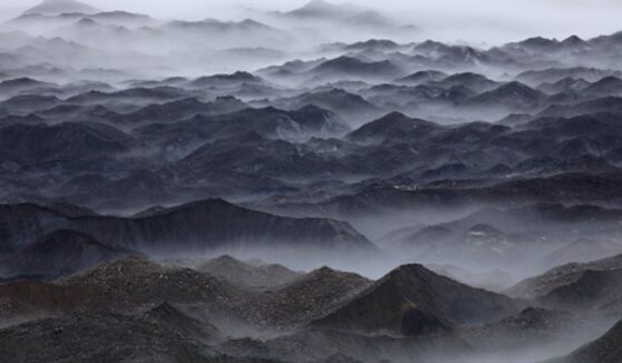 Mountains stand in swaths of fog.