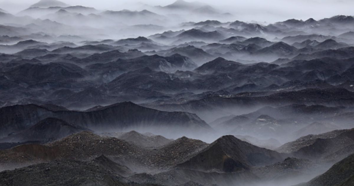 Mountains stand in swaths of fog.