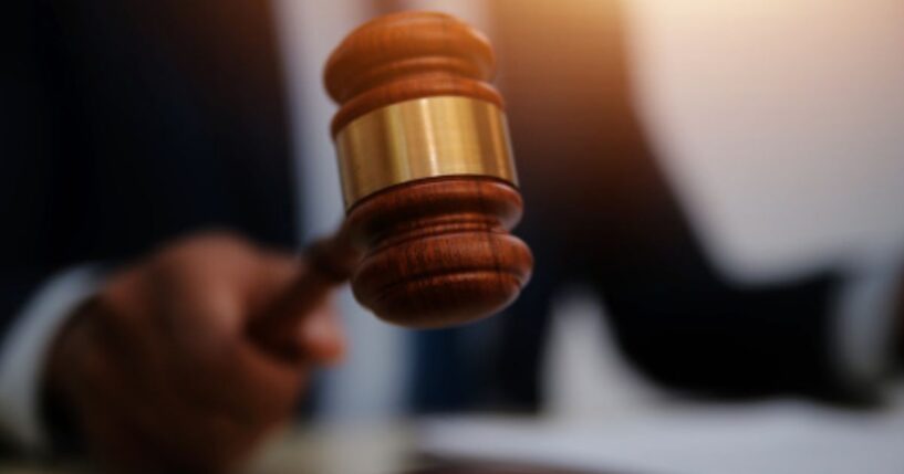 Man slams gavel on a wooden block.