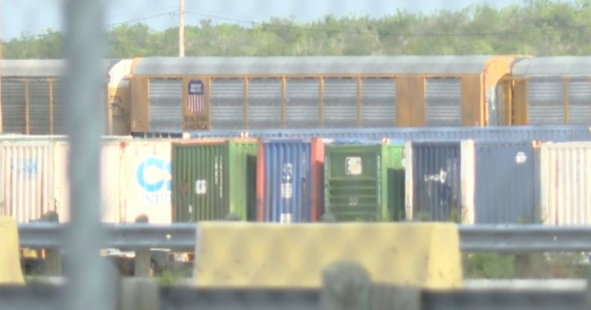 Union Pacific train cars can be spotted through a gate stationed at the rail yard in Laredo, Texas.