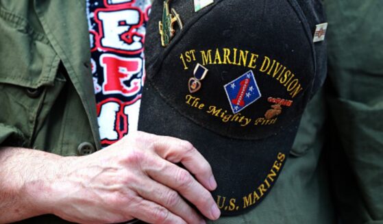 A veteran marine holds his commemorative hat on top of his heart.