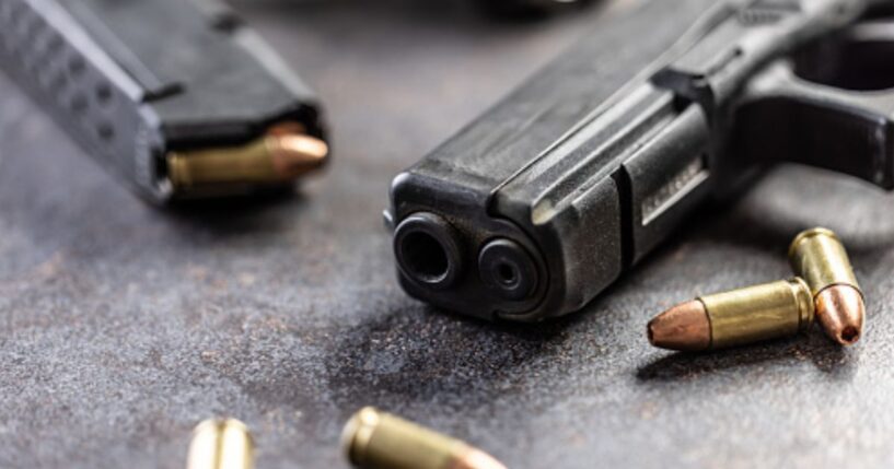Guns and bullets lay on a table.