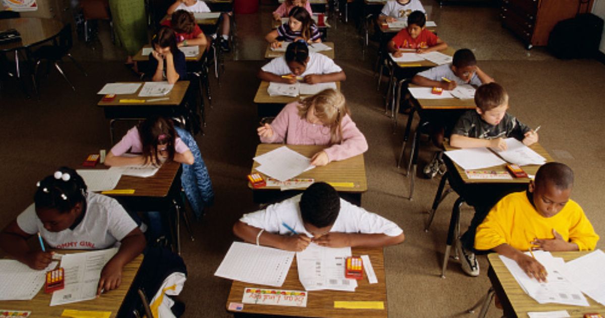 Students sit in a classroom and complete schoolwork.