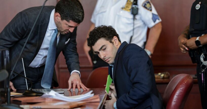 Luigi Mangione squirms in a New York courtroom while his lawyer speaks to him on May 18, 2026.