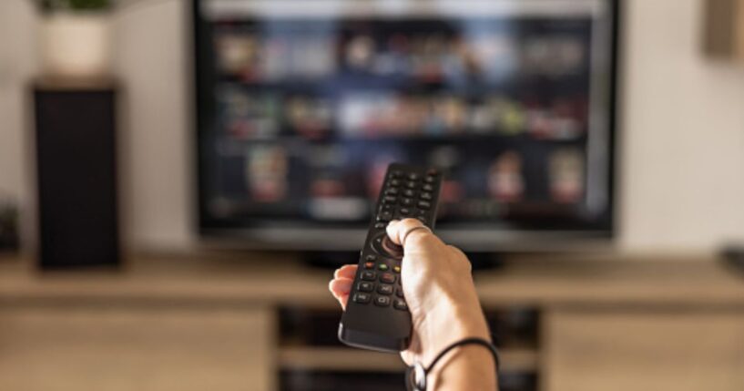 A person turns on a television with a remote control.