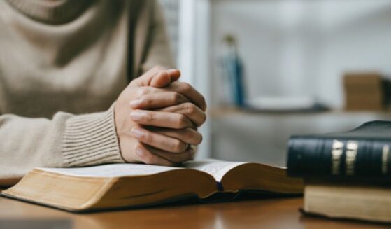 Woman prays with her hands on a Bible.