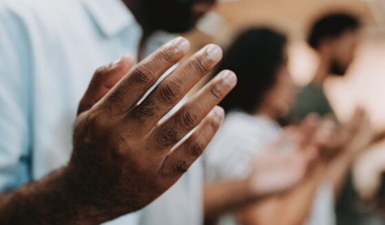 Man and group of fellow Christians gather in a line of prayer.