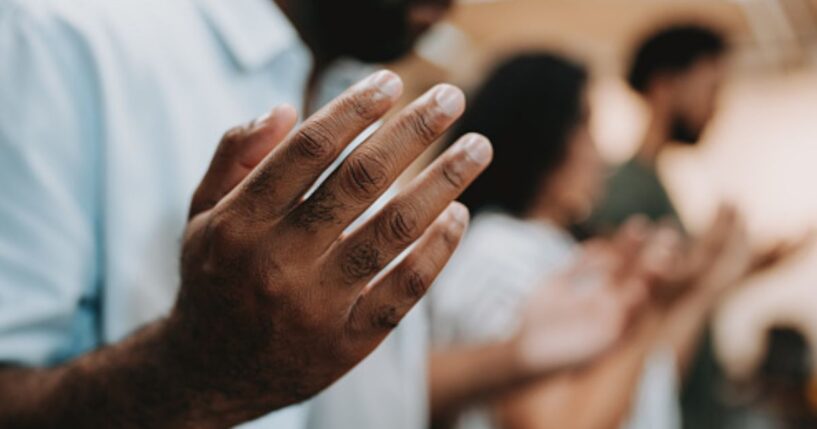 Man and group of fellow Christians gather in a line of prayer.