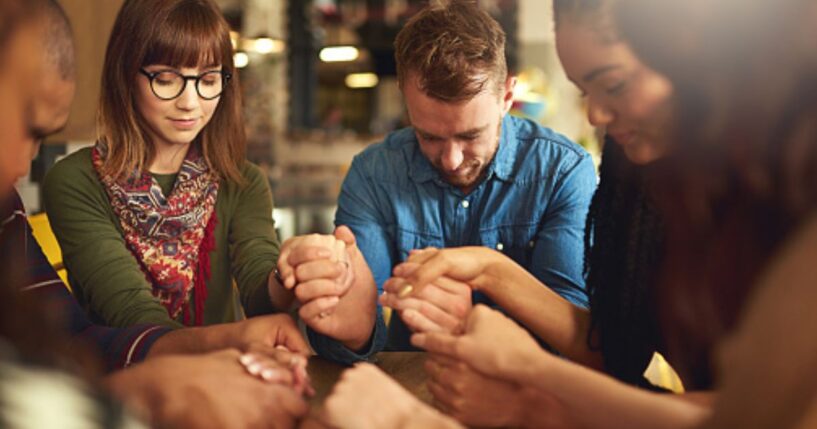 A group of people pray in a circle.