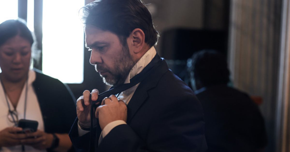 Senator Ruben Gallego ties his tie as he walks to the Senate Chambers on May 11, 2026.