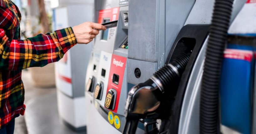 A person pays for gas at a gas station pump using a card.