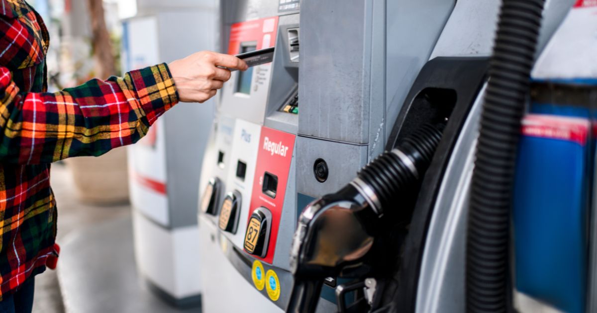 A person pays for gas at a gas station pump using a card.
