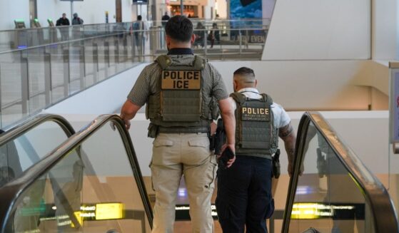 Two ICE agents ride down an escalator at LaGuardia Airport in New York on March 28, 2026.