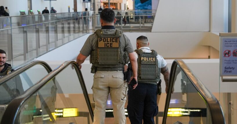 Two ICE agents ride down an escalator at LaGuardia Airport in New York on March 28, 2026.