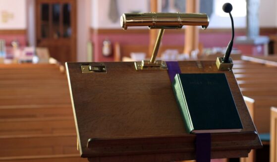 A modern wooden church pulpit with a light, microphone, and Bible on it.