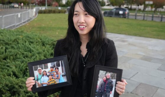 Grace Jin Drexel, the daughter of detained Chinese pastor Jin Mingri, holds up framed photos of Mingri and his family in Washington, DC on Oct. 30, 2025.