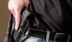 A man draws his gun from a leather holster on his belt.