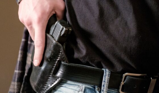 A man draws his gun from a leather holster on his belt.