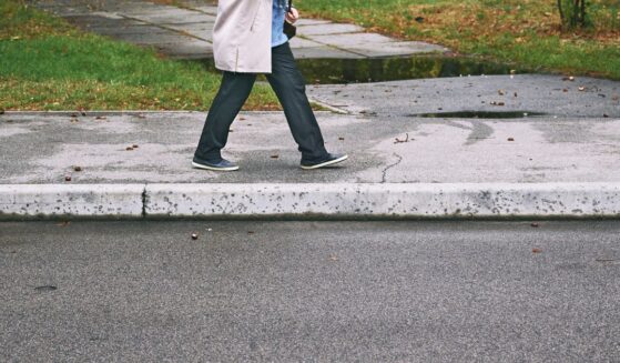 A person walks on a sidewalk during the daytime.