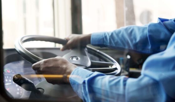 A bus driver holds the steering wheel of the bus with both hands.