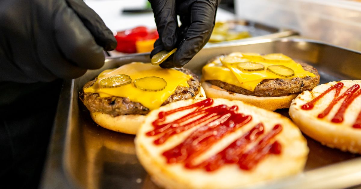 Close-up of hands assembling a fast food burger.
