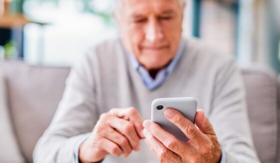 An elderly man looks at his phone.