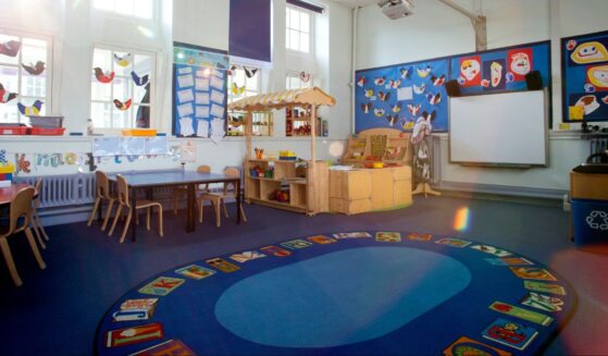 An image of an empty nursery classroom with a rug in the middle of the floor.