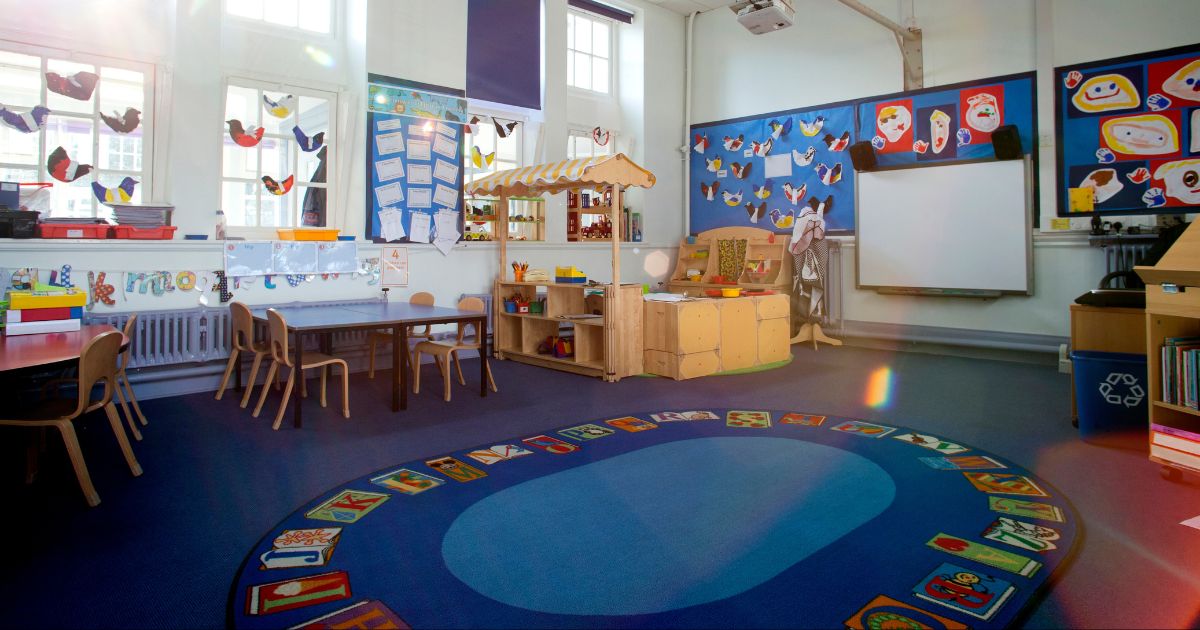 An image of an empty nursery classroom with a rug in the middle of the floor.