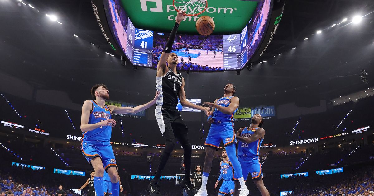 Victor Wembanyama of the San Antonio Spurs dunks the ball between Chet Holmgren and Jalen Williams of the Oklahoma City Thunder during the first half in Game One of the NBA Western Conference Finals at Paycom Center on May 18, 2026, in Oklahoma City, Oklahoma.