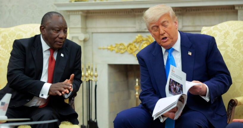 President of South Africa Cyril Ramaphosa looks on as President Donald Trump displays articles he says report violence against white South Africans in the Oval Office of the White House on May 21, 2025, in Washington, D.C.
