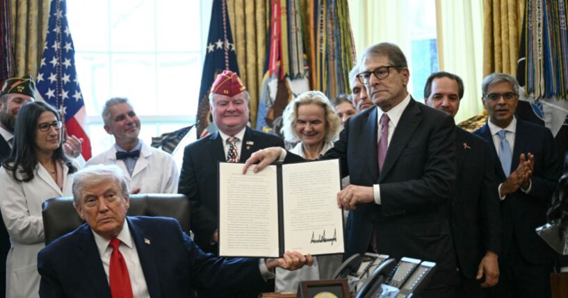 President Donald Trump and Howard Kessler, founder of the Commonwealth Project, hold up an executive order easing restrictions on marijuana in the Oval Office at the White House in Washington, D.C., on Dec. 18, 2025.