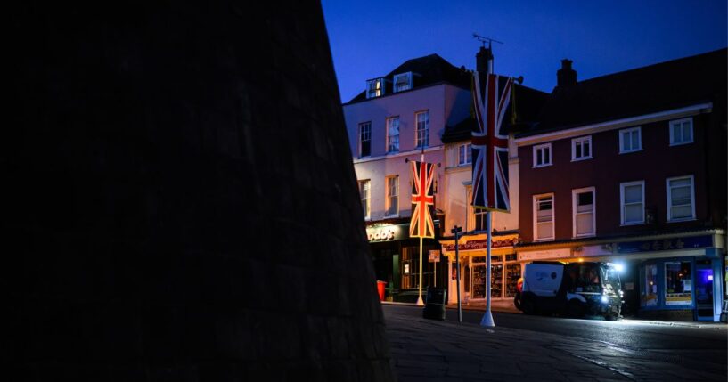 United Kingdom banners are illuminated by a headlight in the street outside Windsor Castle on Sept. 12, 2025, in Windsor, England.