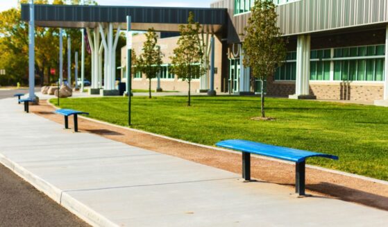 A high school with a bus stop and benches in the United States.