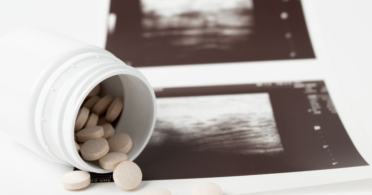 Abortion pills are depicted in front of an ultrasound.