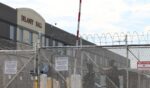 Immigration and Customs Enforcement agents stand guard behind the gate as protestors gather at Delaney Hall, which is being used as an Immigration and Customs Enforcement detention center in Newark, New Jersey, on May 26, 2026.